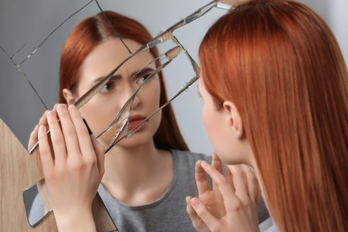 Sad,Young,Woman,Suffering,From,Mental,Problems,Near,Broken,Mirror